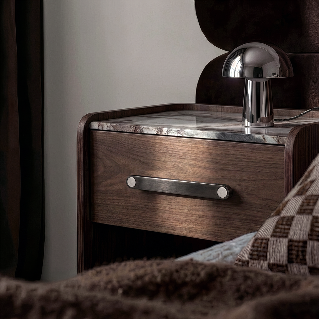 Gunmetal Ensemble cabinet handle with steel button details on a timber bedside drawer